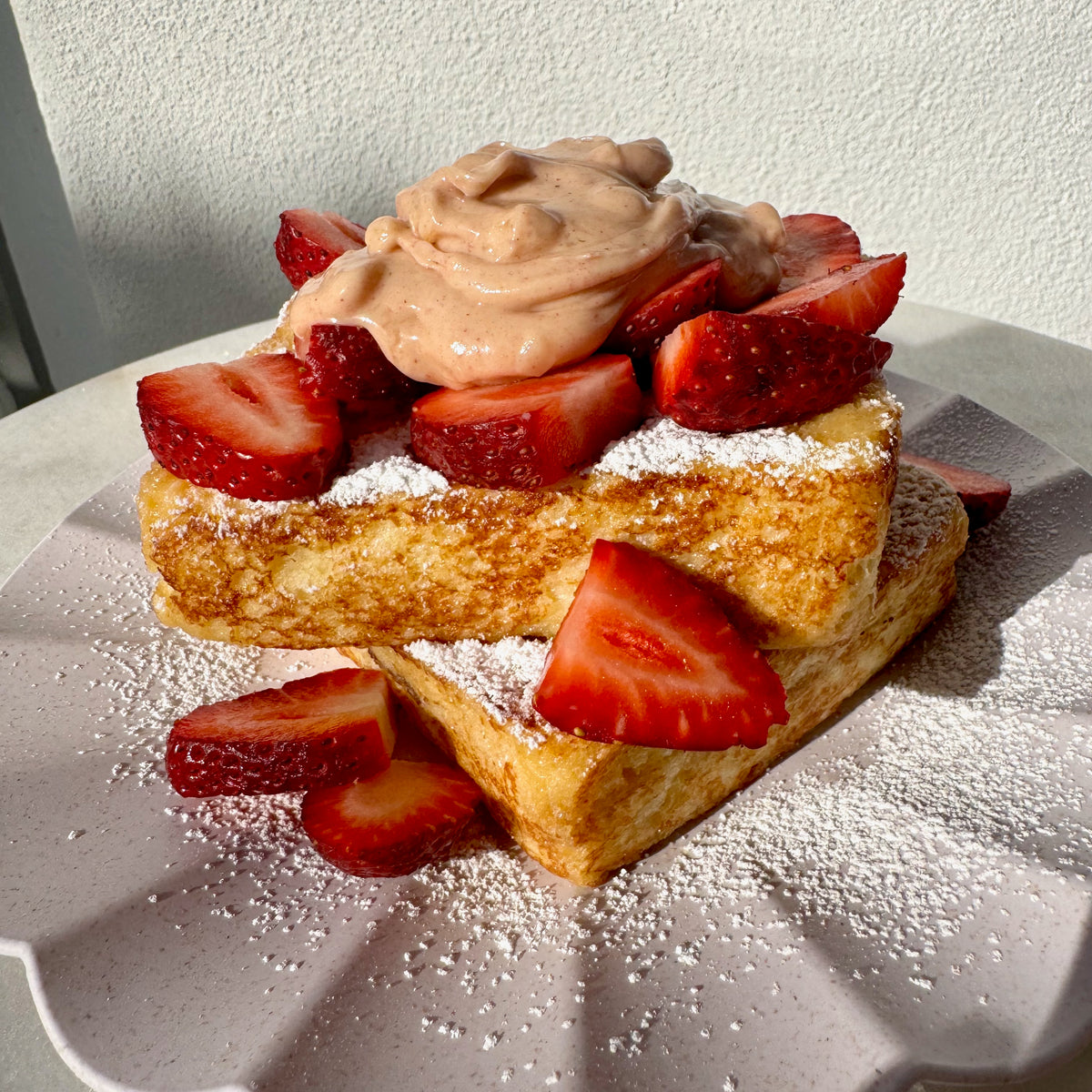 Strawberry and macadamia stuffed French toast topped with sliced strawberries and icing sugar.