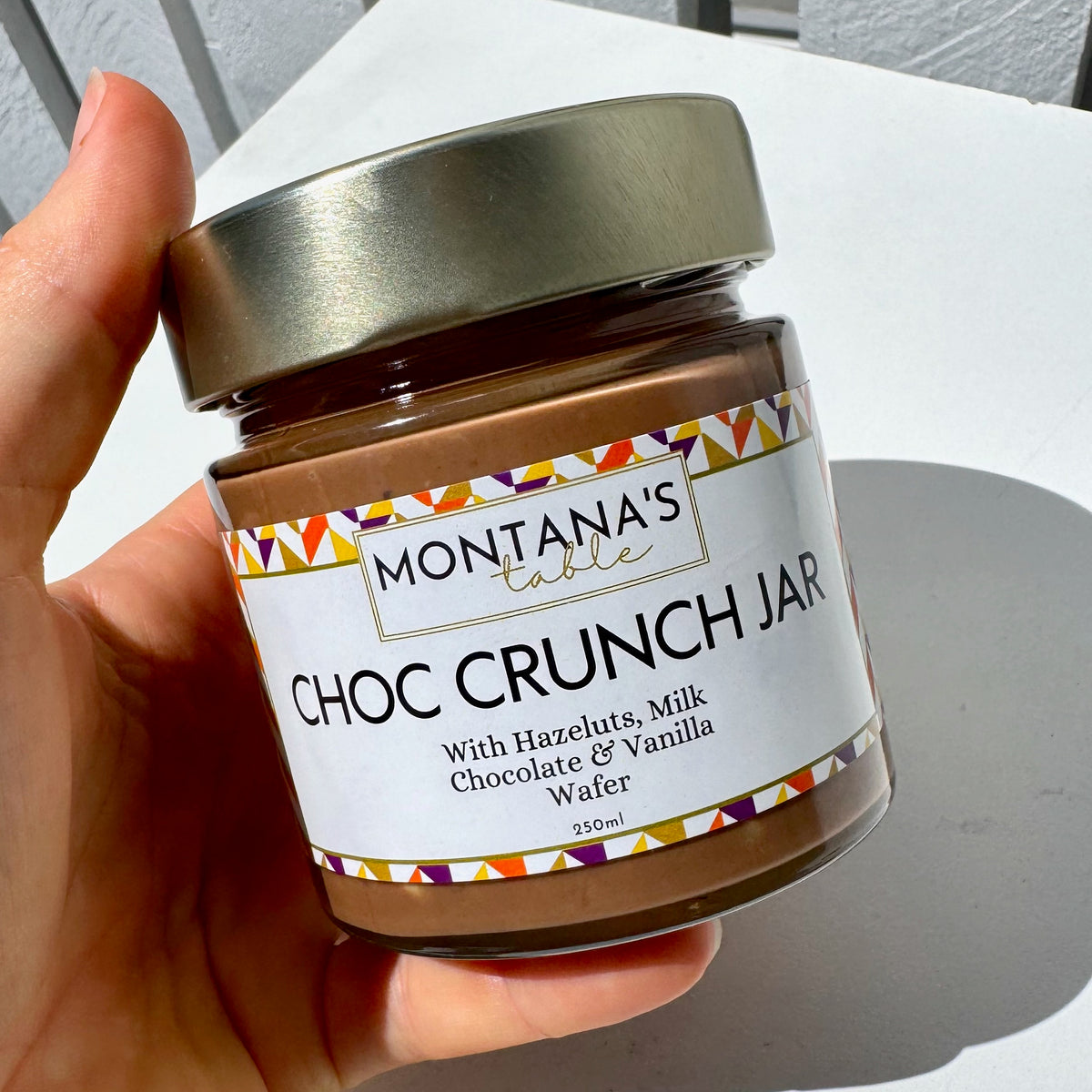 Hand holding Milk Chocolate Hazelnut Crunch Jar by Montana's Table